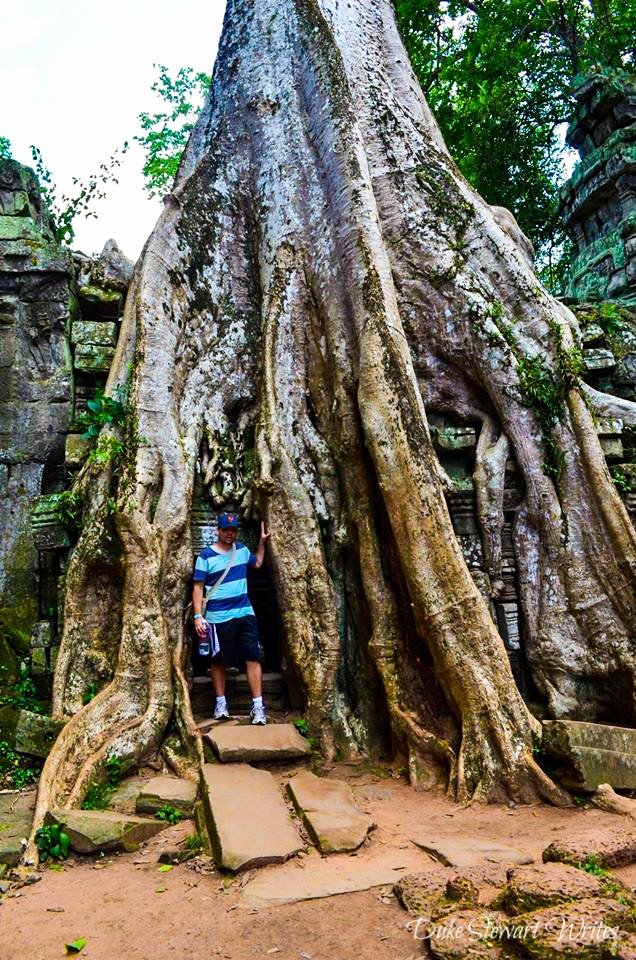 Duke Stewart next to overgrown tree at Ta Prohm